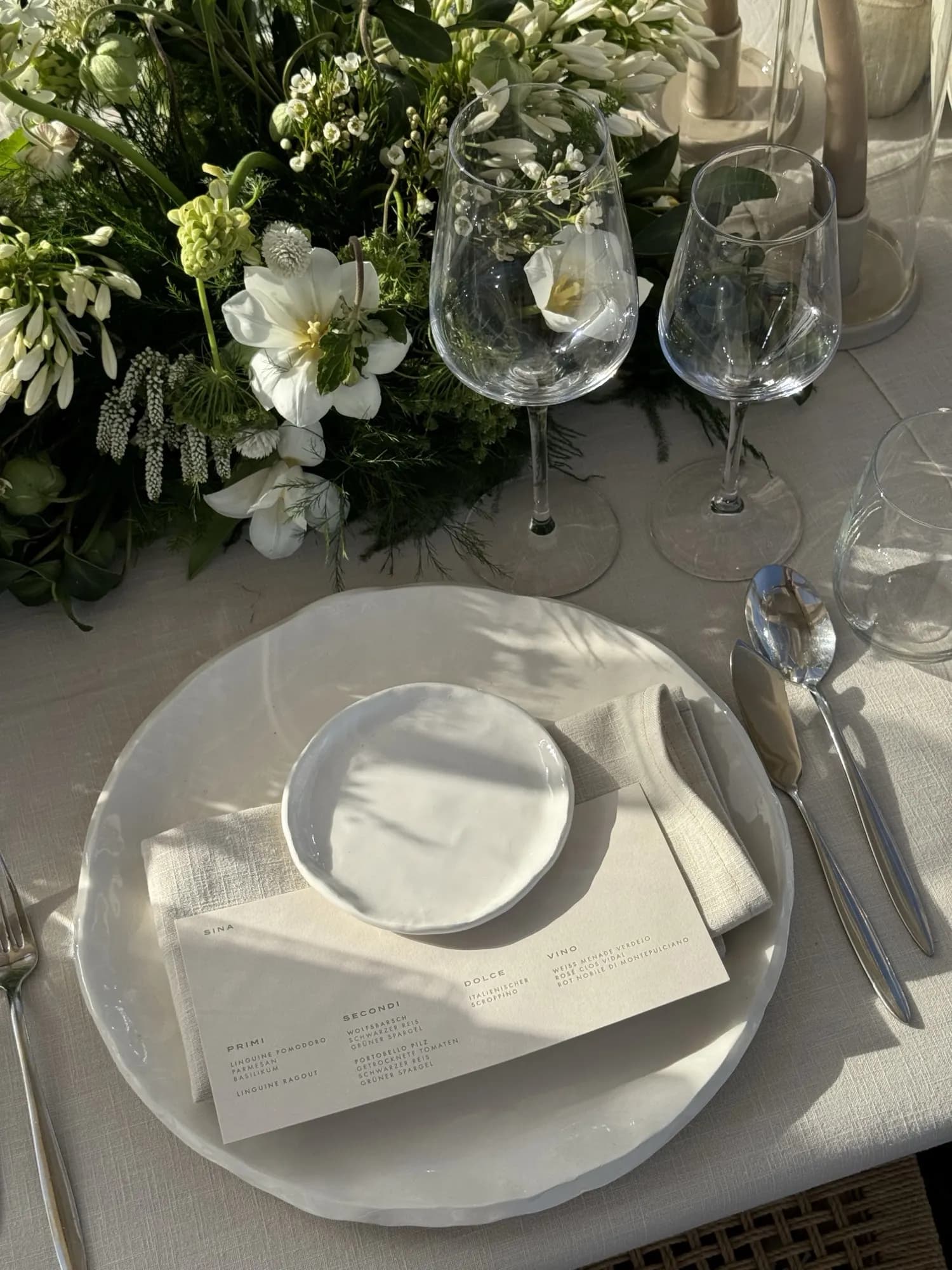 A sunlit wedding place setting with white flowers