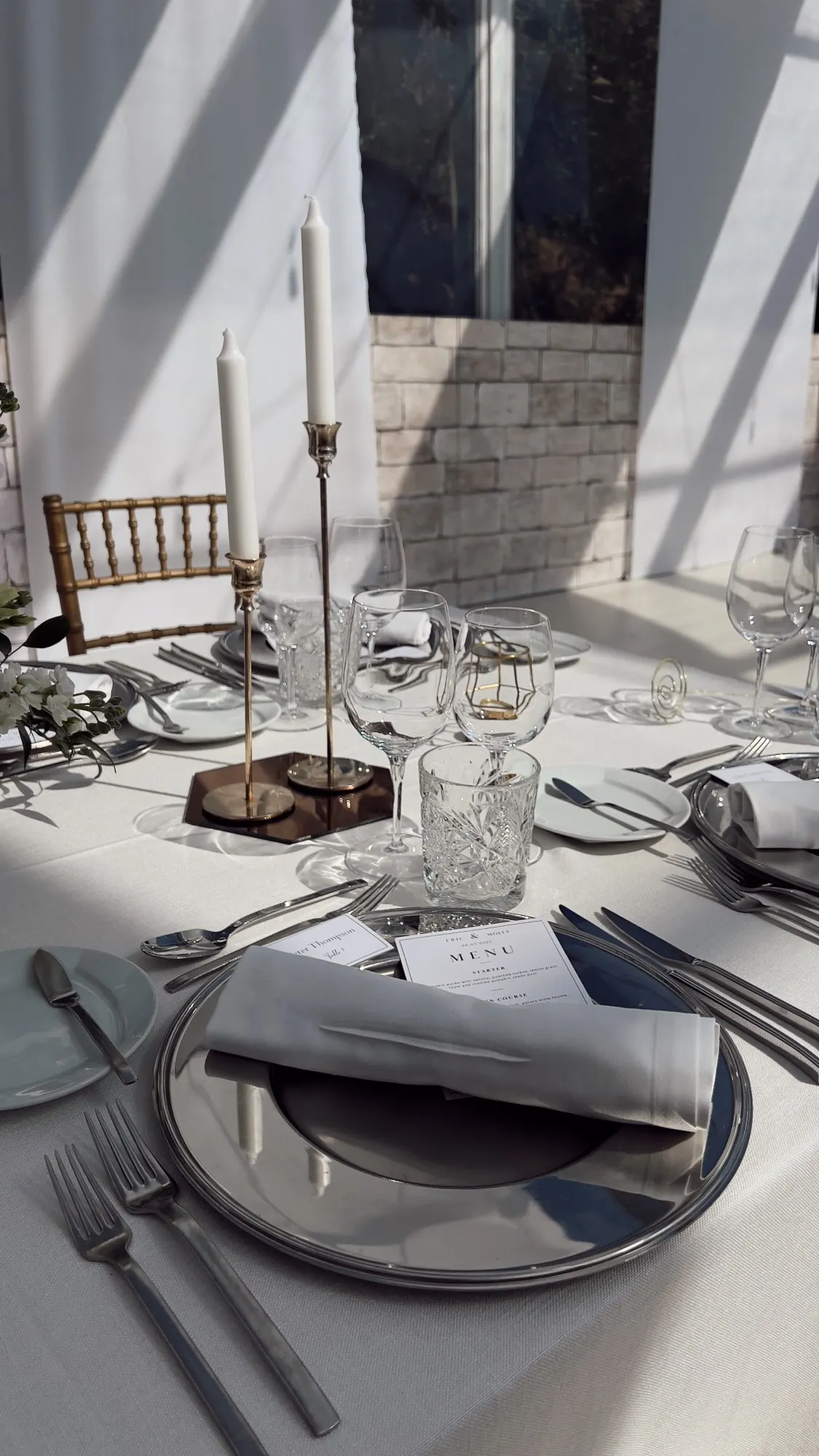 A wedding place setting with a menu card and brass candlesticks