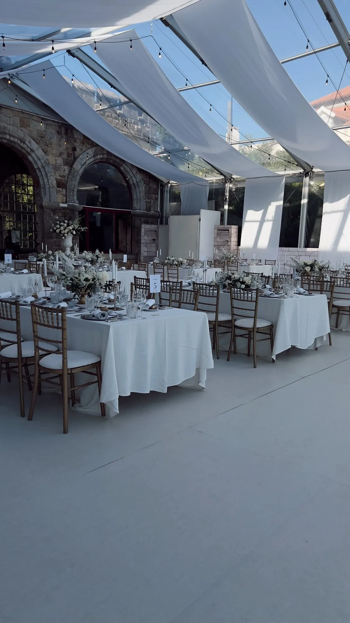 A draped marquee reception with white tables and chairs